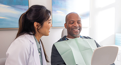 A dentist and patient in a dental clinic, engaged in conversation.