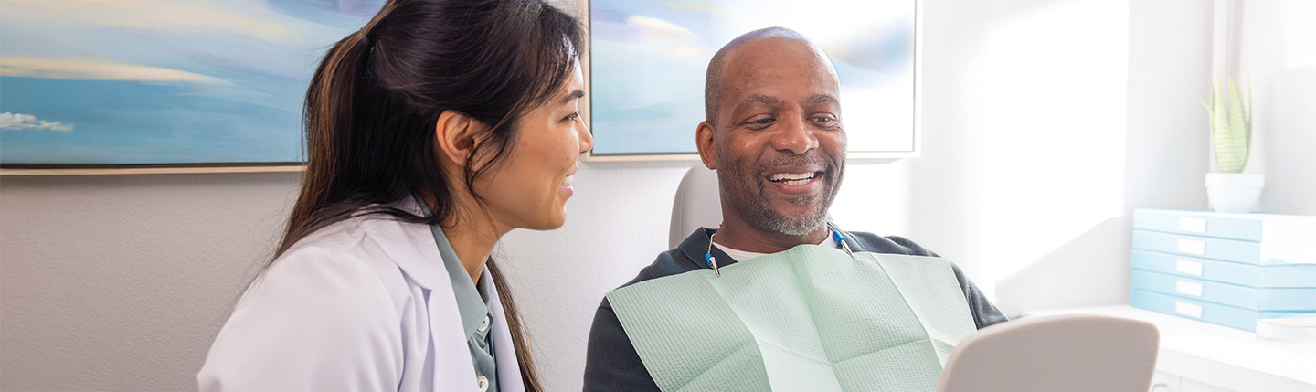 A dentist and patient in a dental clinic, engaged in conversation.